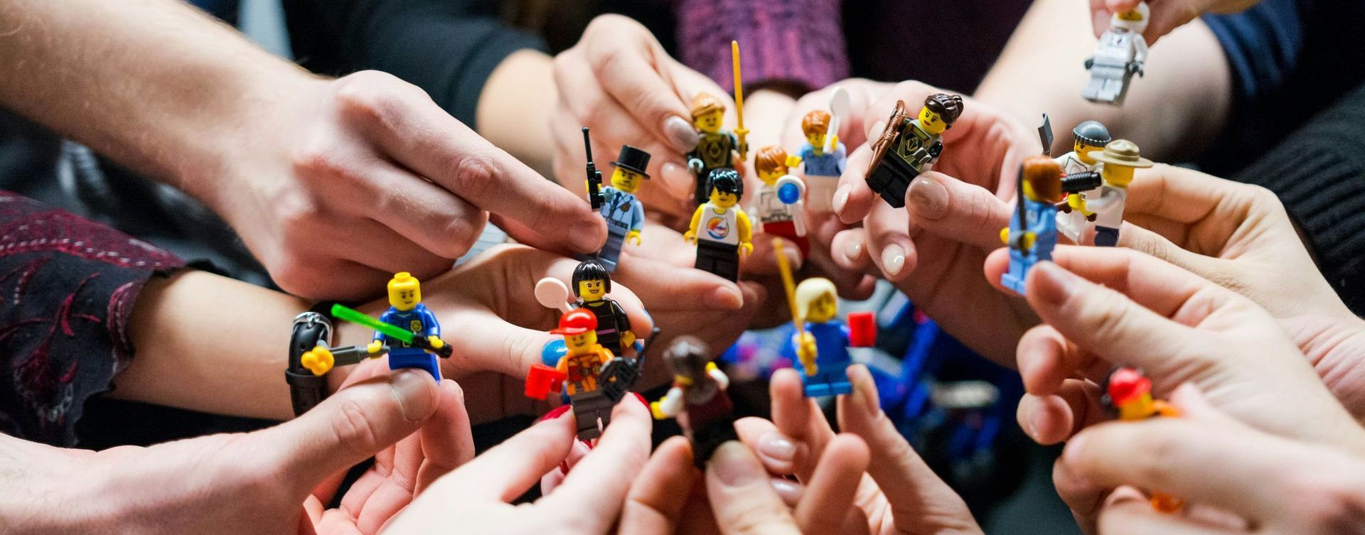 A group of people are holding lego figures in their hands.