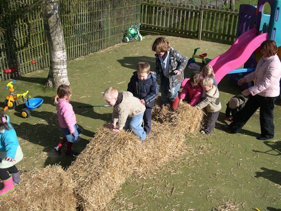 A group of children are playing with hay bales in a playground.