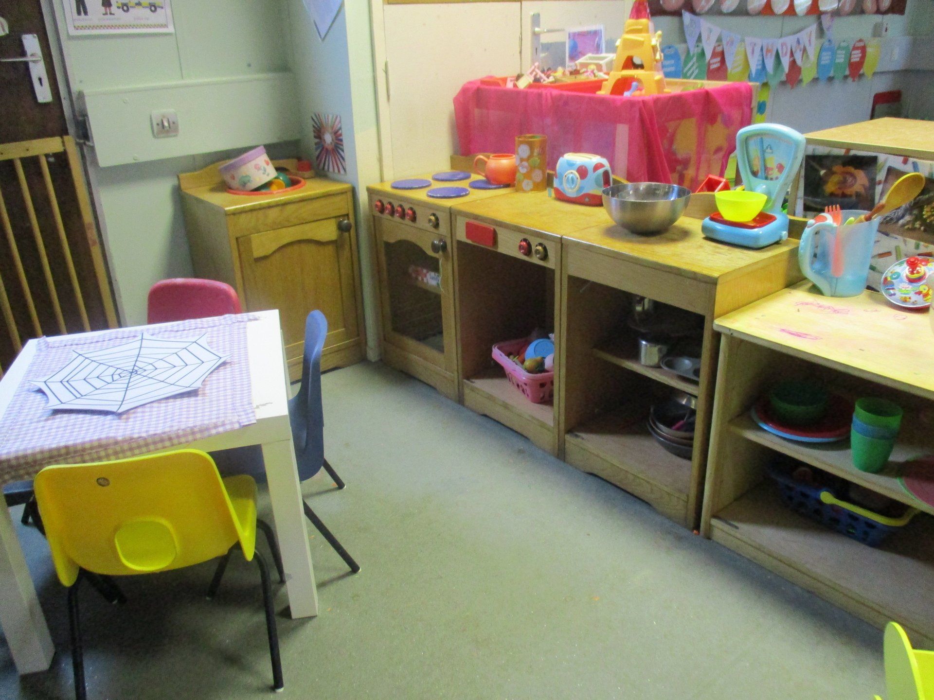 A room with a table and chairs and a play kitchen