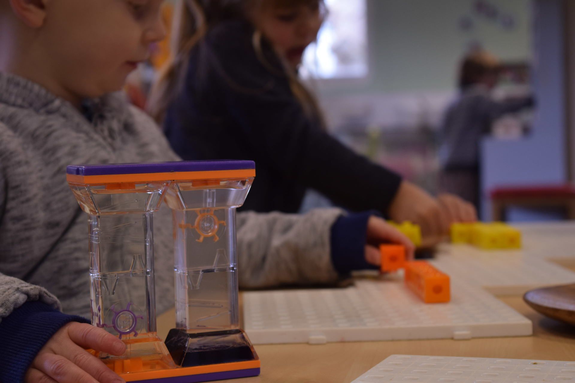 A young boy is playing with a water timer at a table.