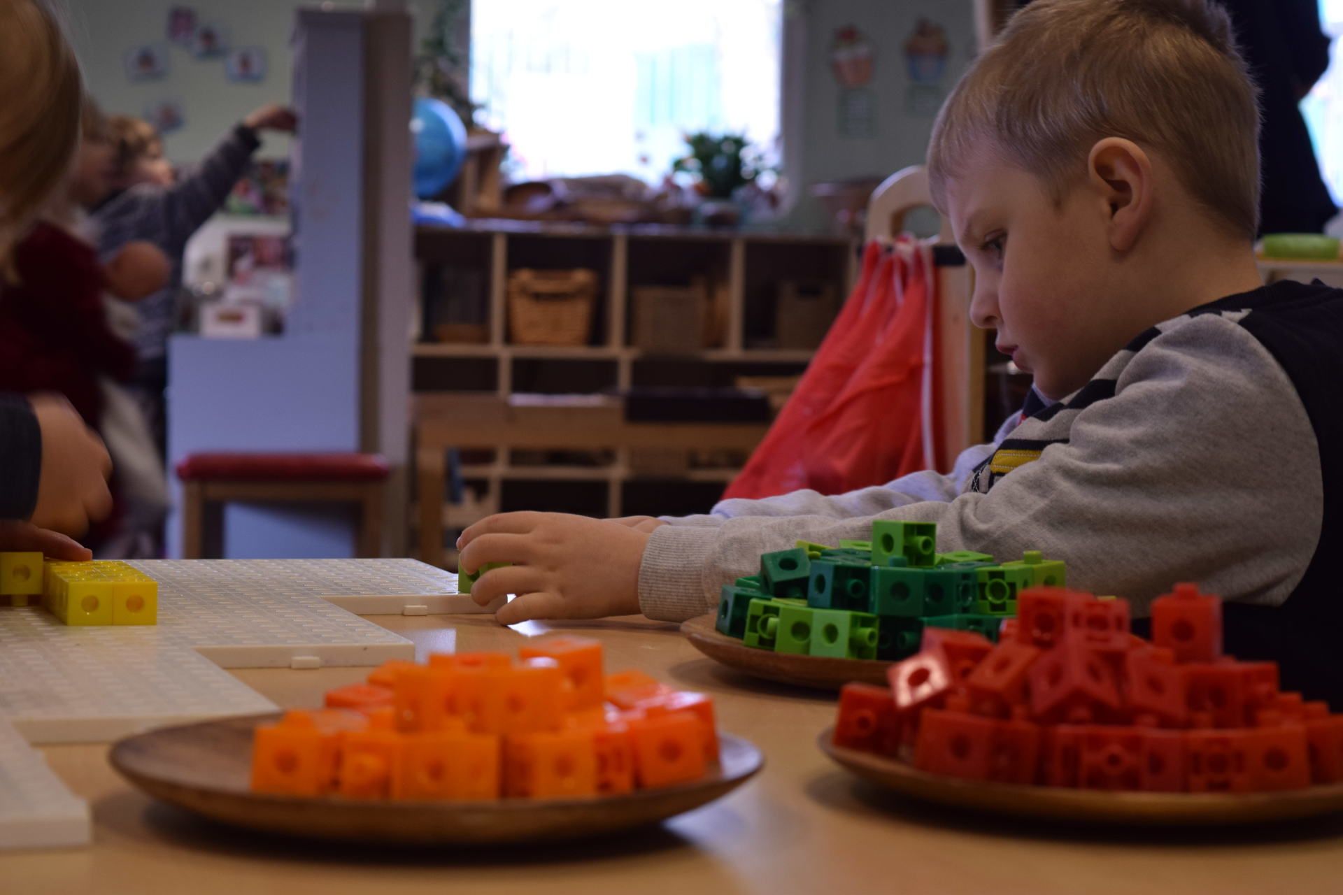 A young boy is sitting at a table playing with blocks.