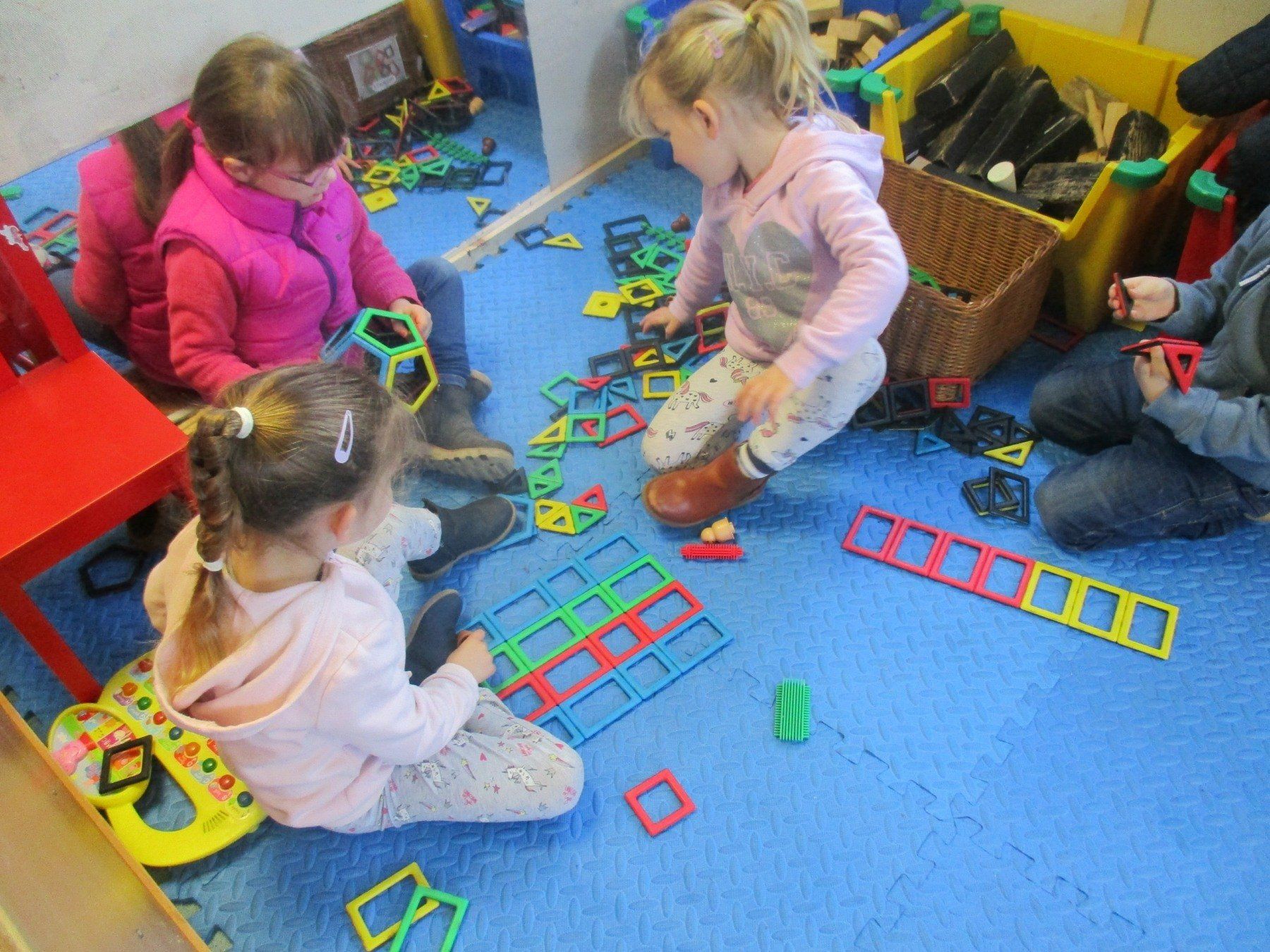 A group of children are sitting on the floor playing with toys.