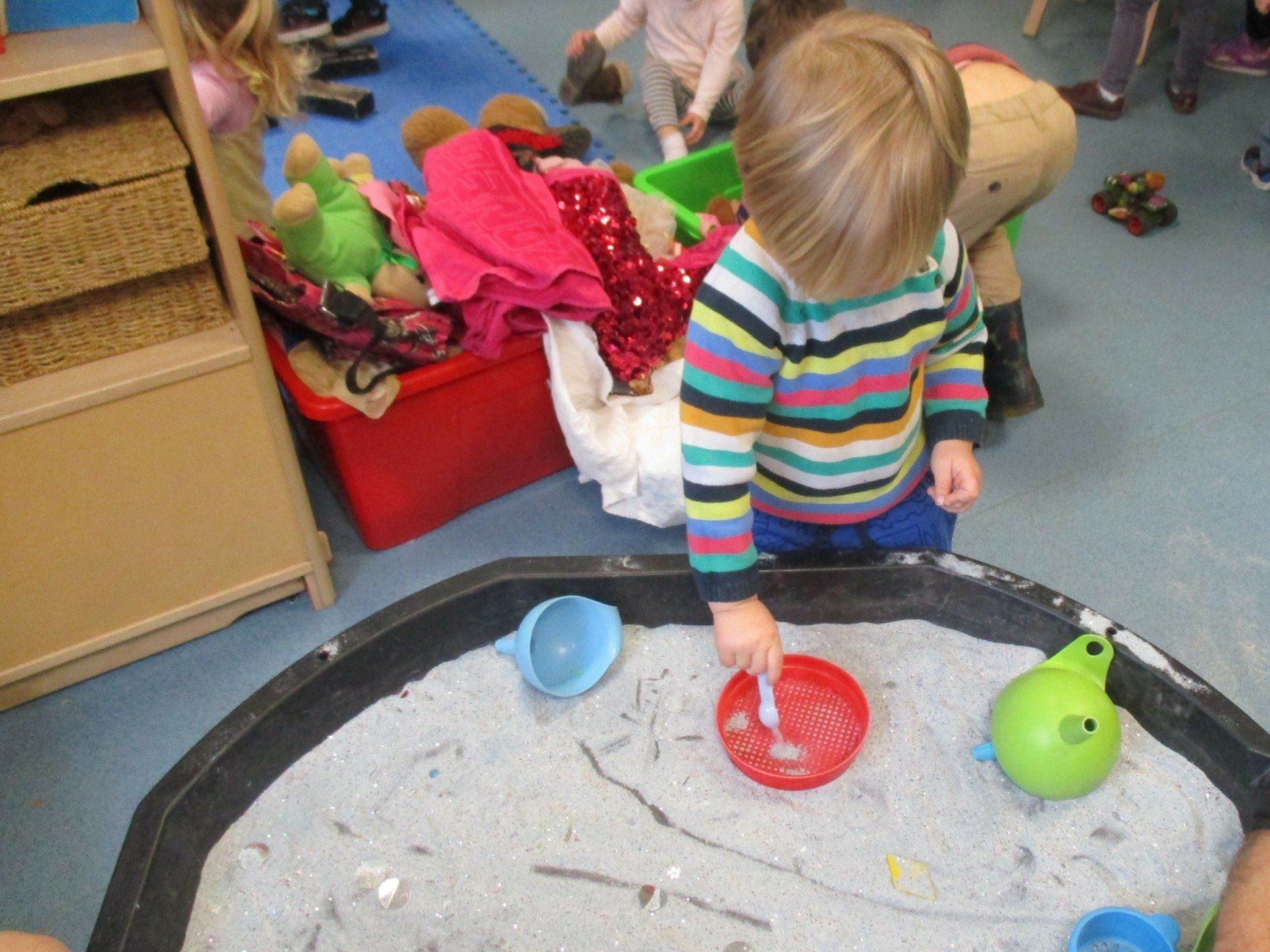A young boy is playing with sand in a sandbox