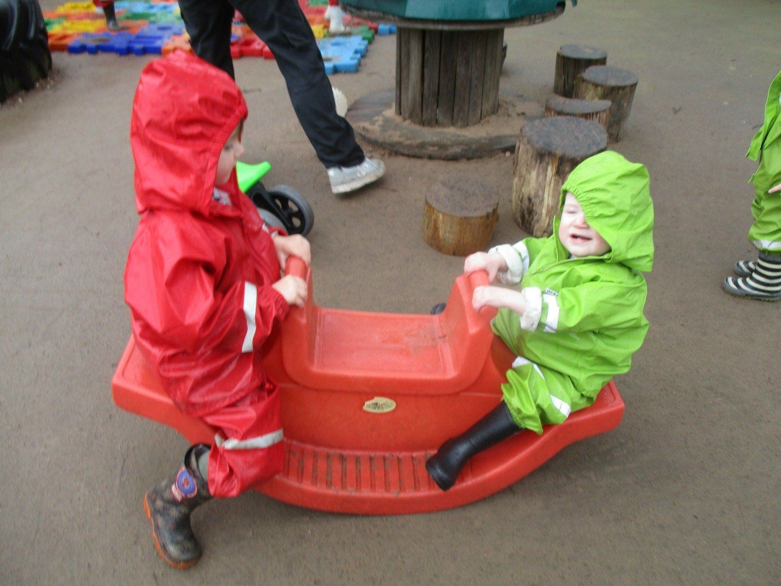 Two children are playing on a red rocking horse