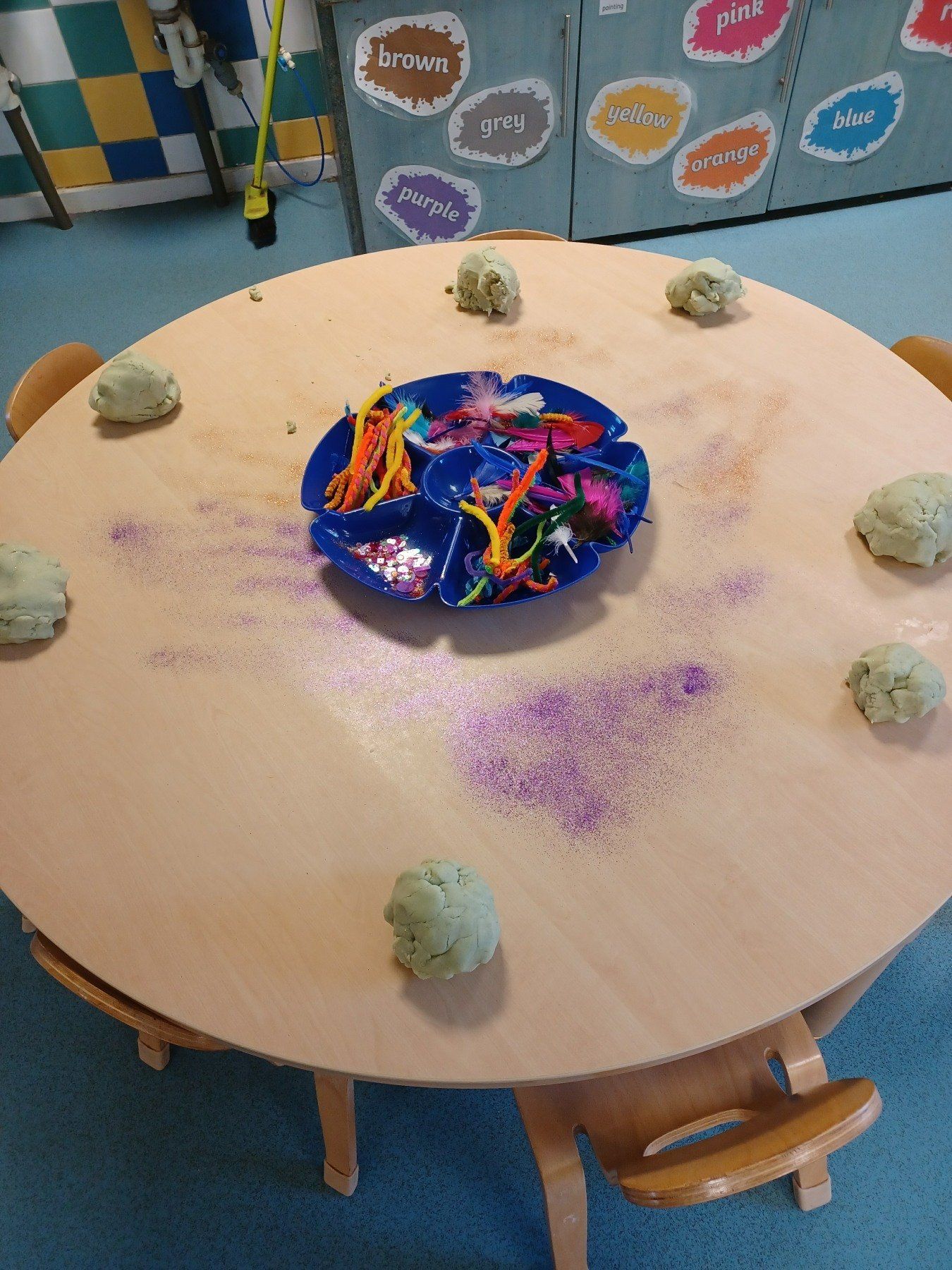 A round wooden table with a tray of toys on it
