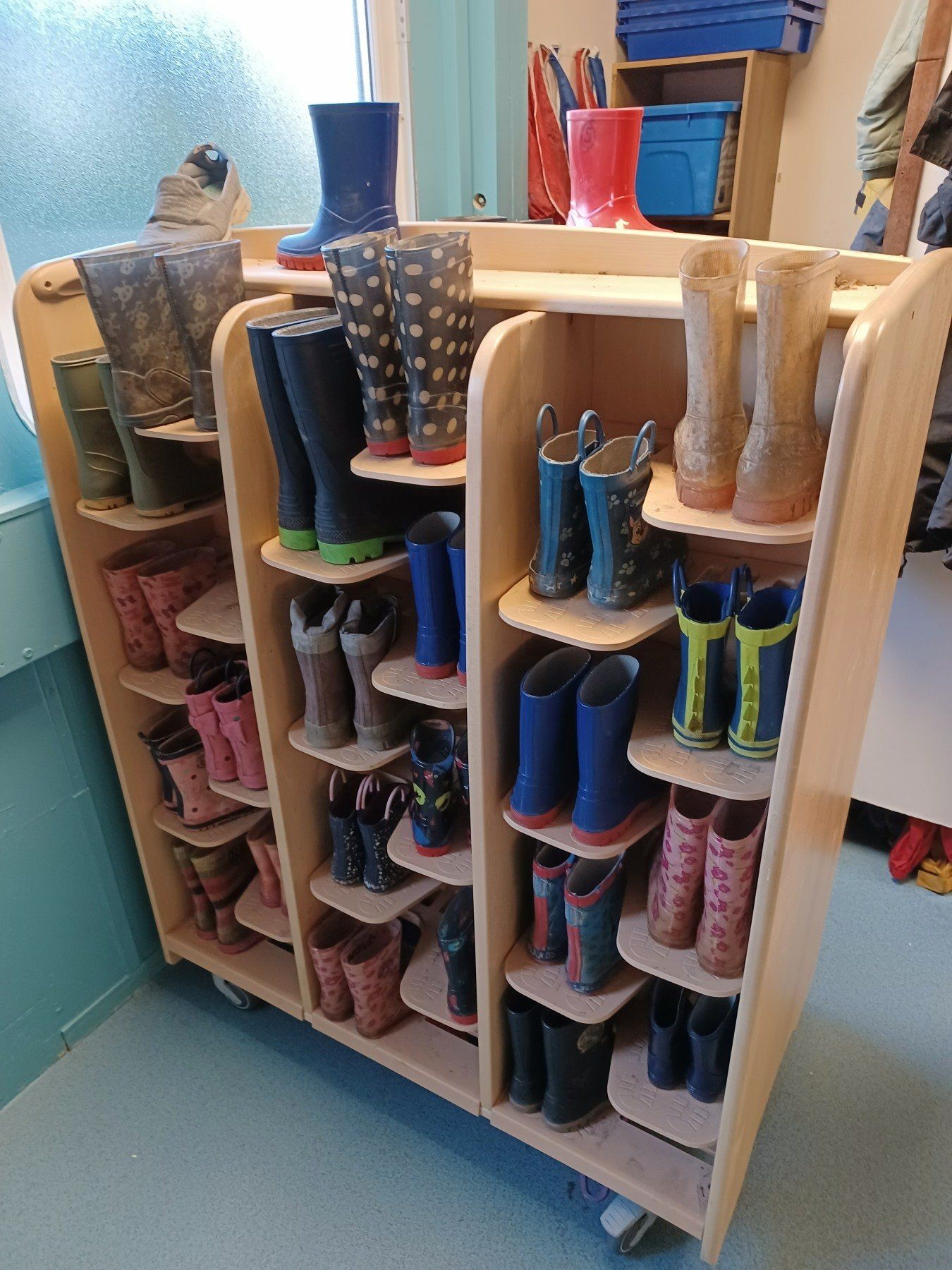A wooden shelf filled with lots of different colored rain boots.
