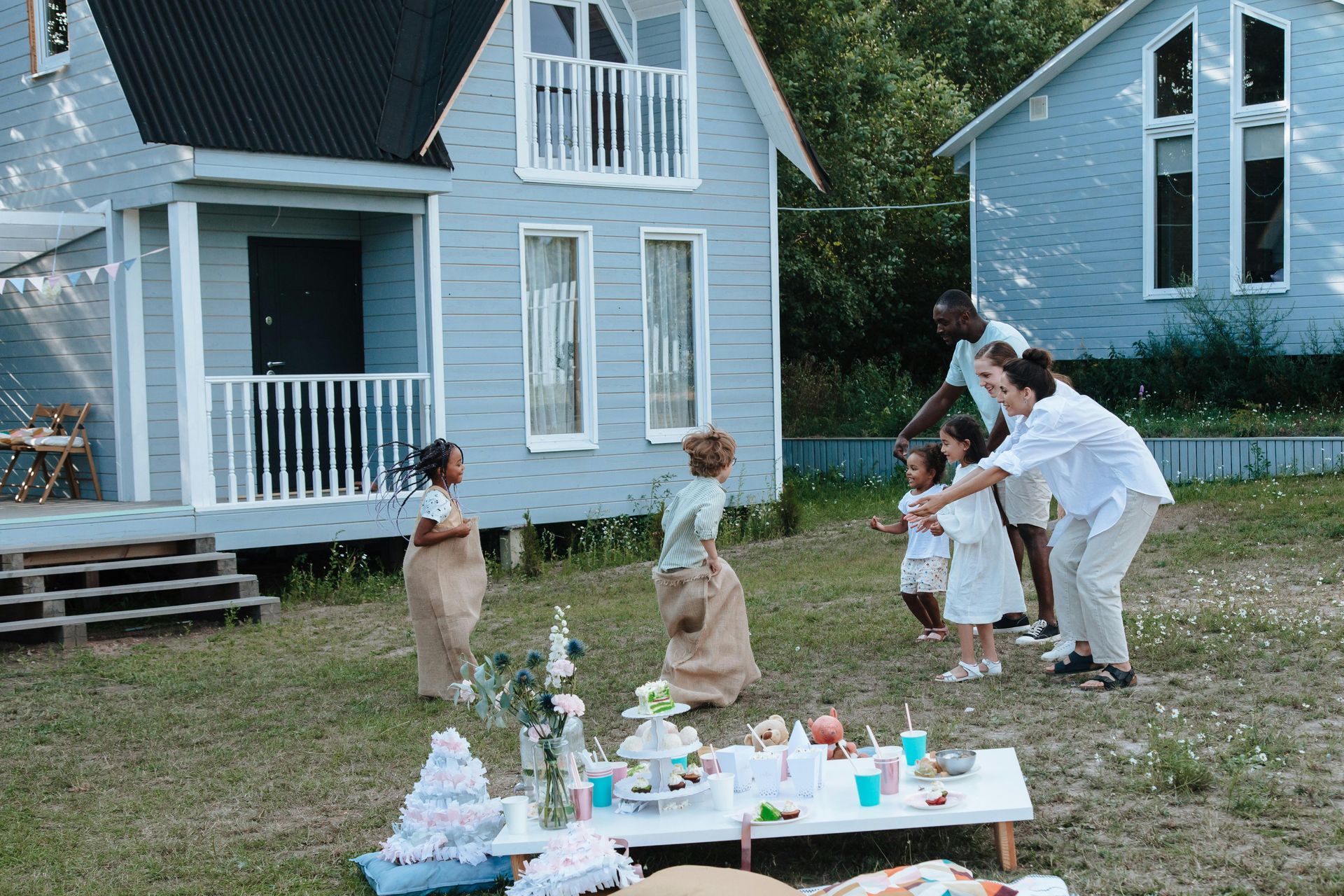 A family is playing with soap bubbles in front of a house.