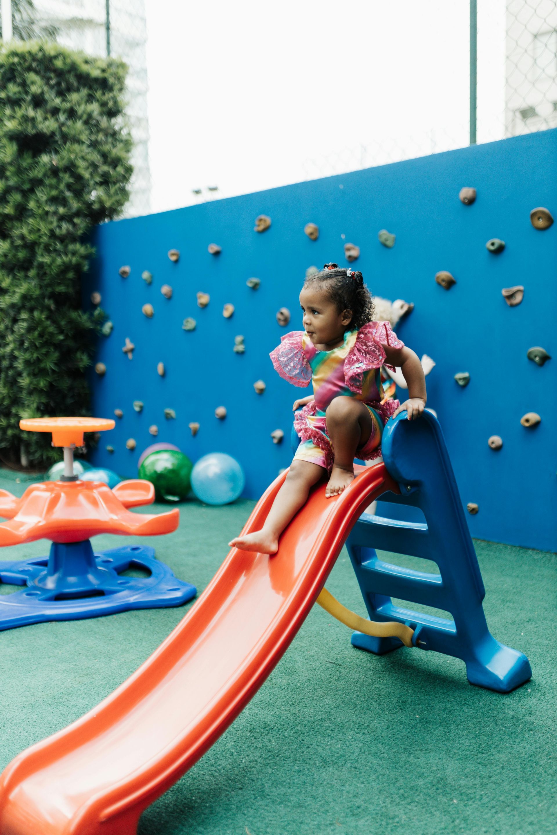 A little girl is playing on a slide in a playground.