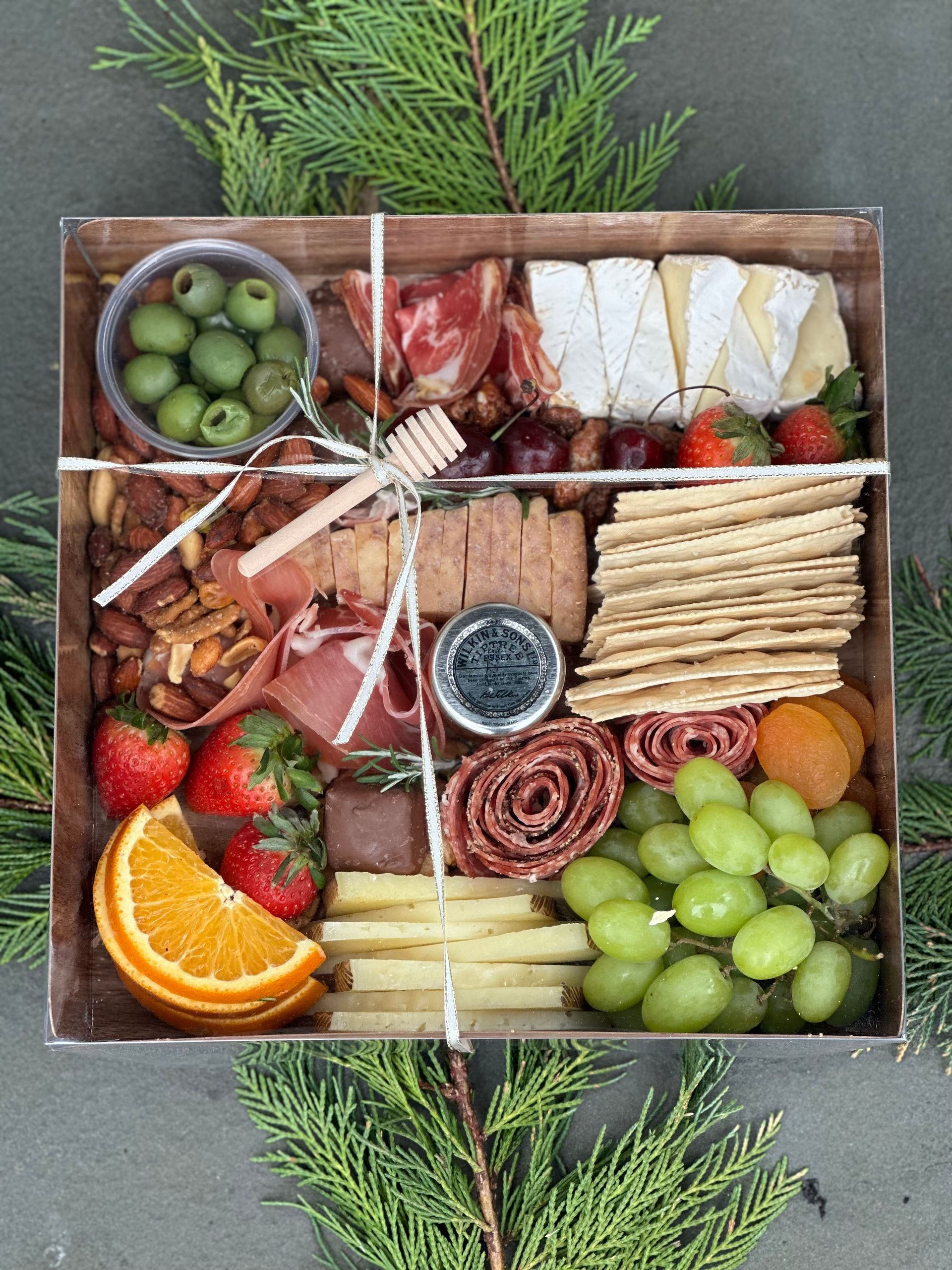 a charcuterie board box filled with a variety of food including grapes and crackers
