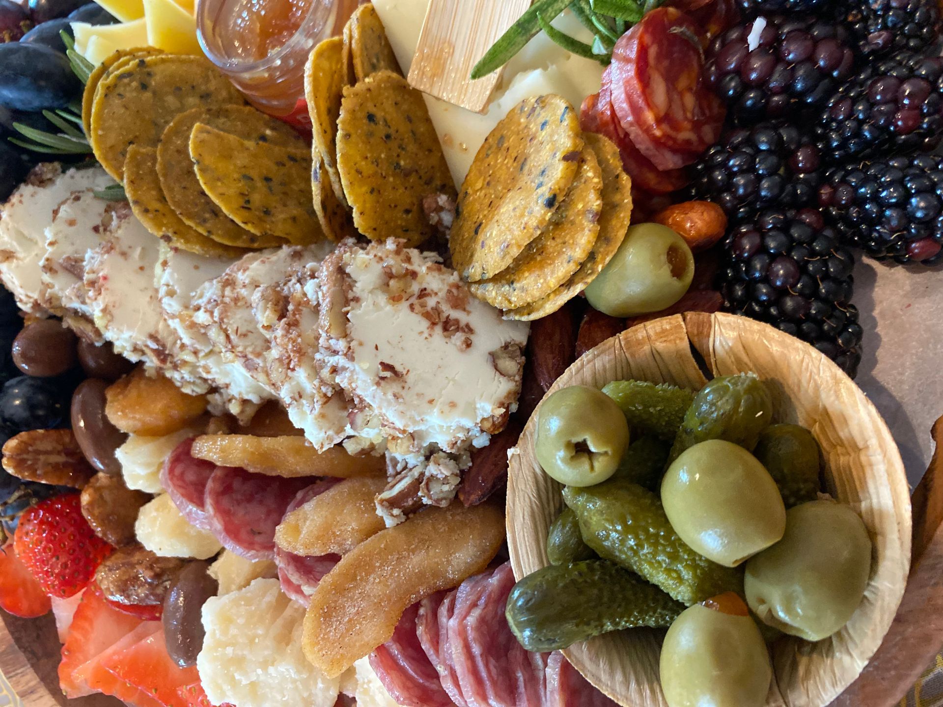 a tray of charcuterie board food including crackers olives and fruit