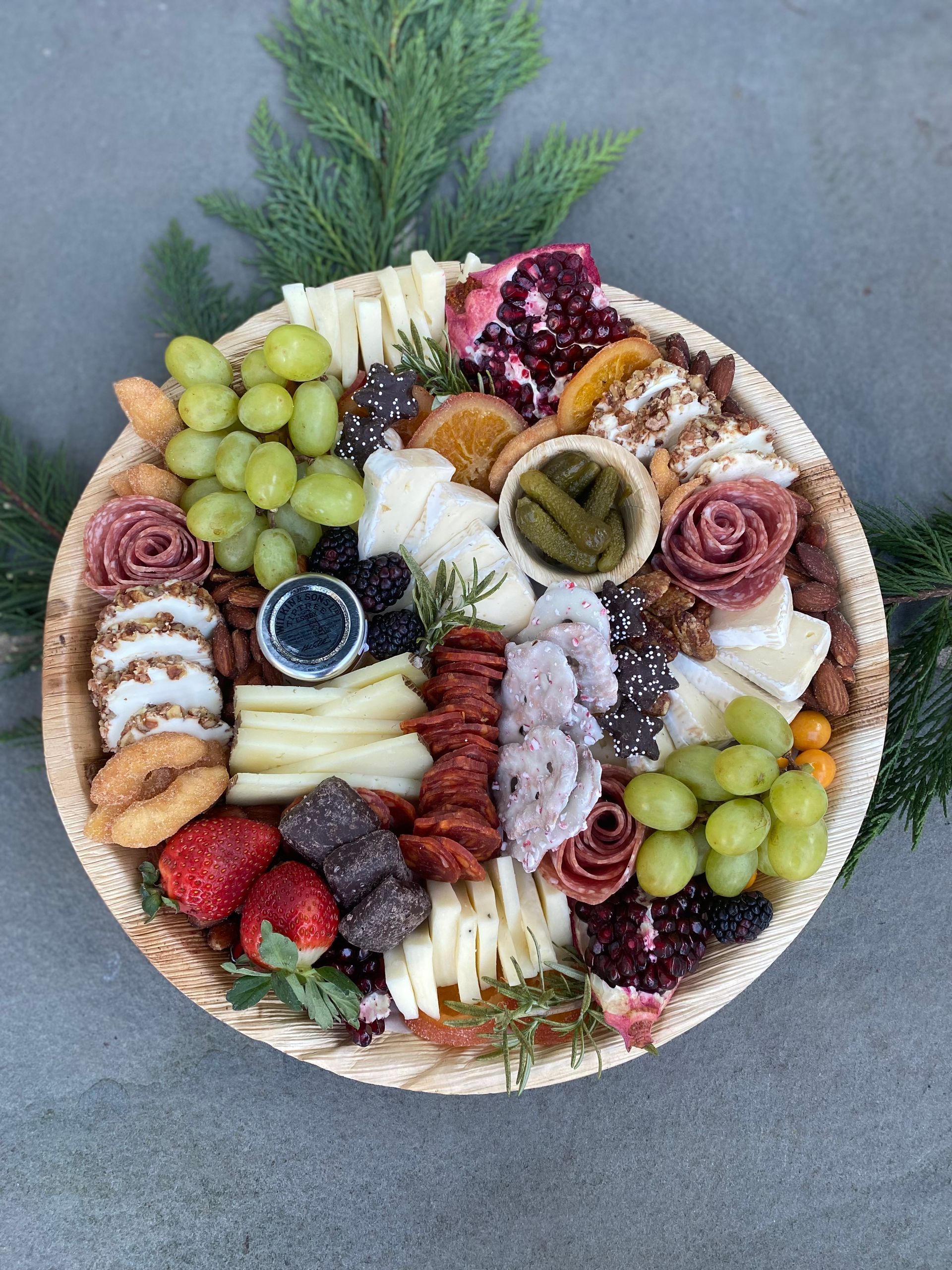 a wooden tray filled with a variety of food including grapes