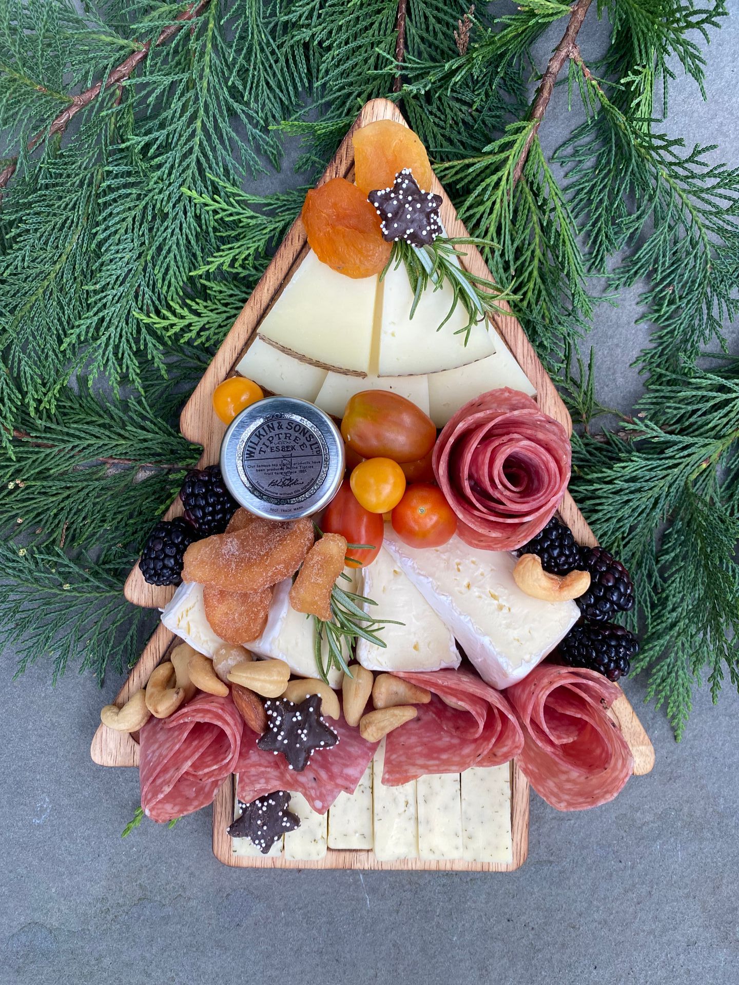 a christmas tree shaped charcuterie board cutting board filled with meats and cheeses