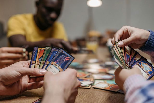 Hands holding colorful trading cards over a table during a card game round