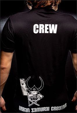 Black t-shirt with "CREW" text and a logo on the back; person's torso and arms visible.