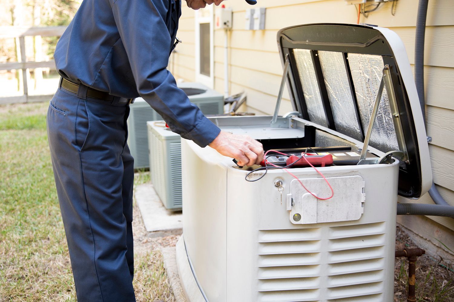 A man is working on a generator outside of a house.