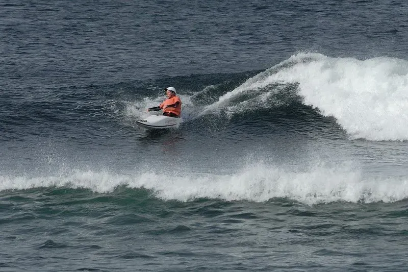 Paddler Northern Ireland | A man is riding a wave on a jet ski in the ocean.