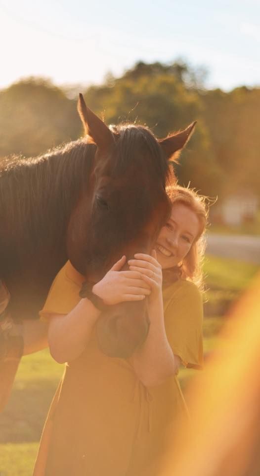 A woman is hugging a horse in a field.