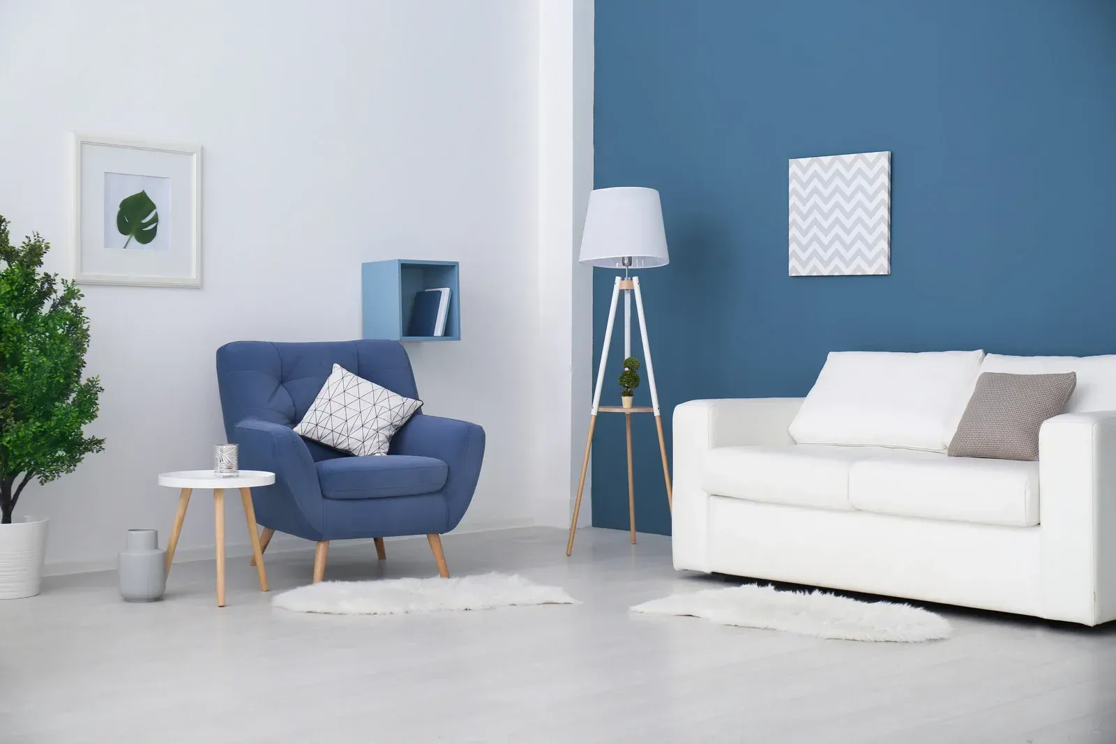 Living room with blue and white walls, blue armchair, white sofa, small table, floor lamp, and rug.