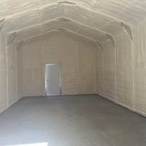 A large empty room with a door and walls covered in spray foam.