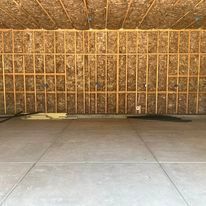 An empty garage with a concrete floor and a wooden wall.