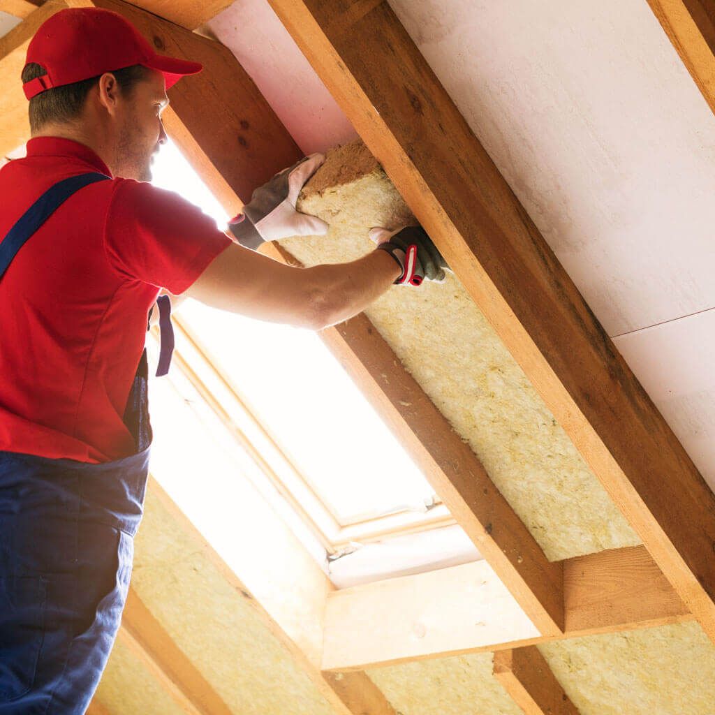 A man is installing insulation on the ceiling of a house.