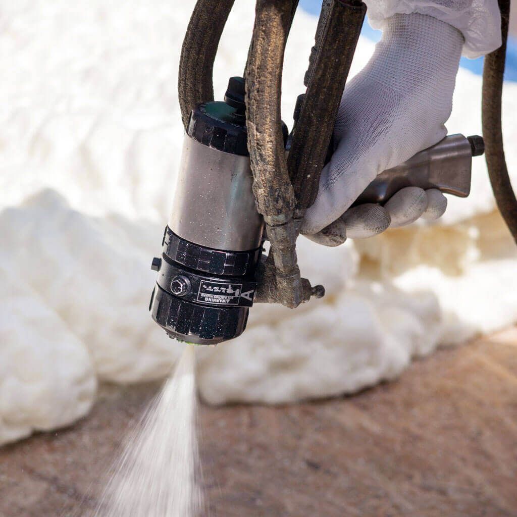 A person is spraying foam on a wooden surface