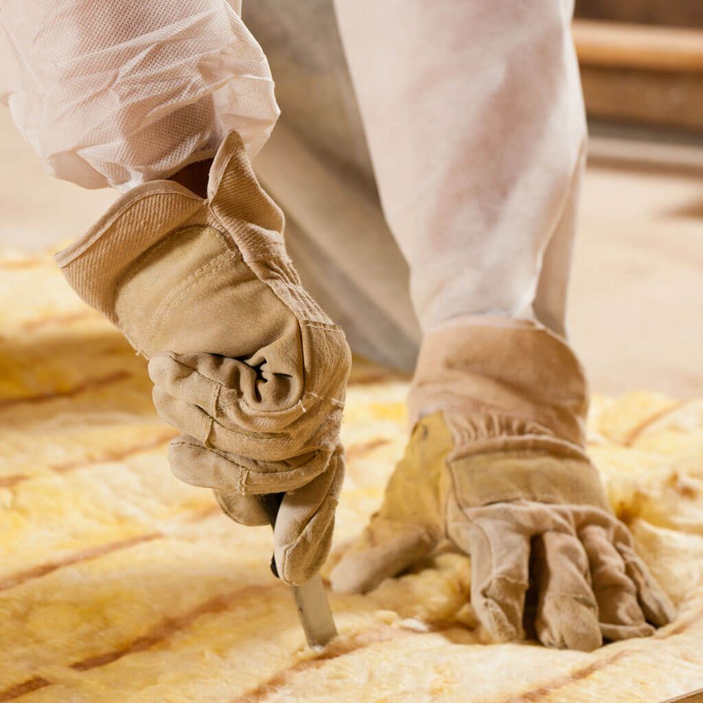 A person wearing gloves is cutting a piece of insulation.
