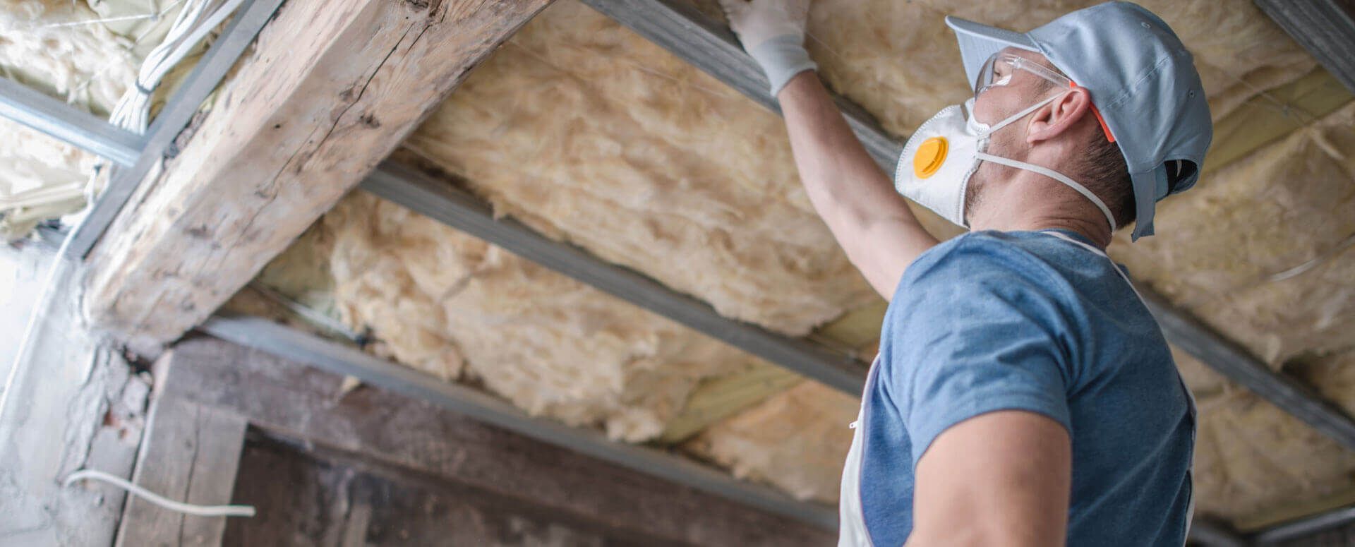 A man wearing a mask is working on the ceiling of a building.