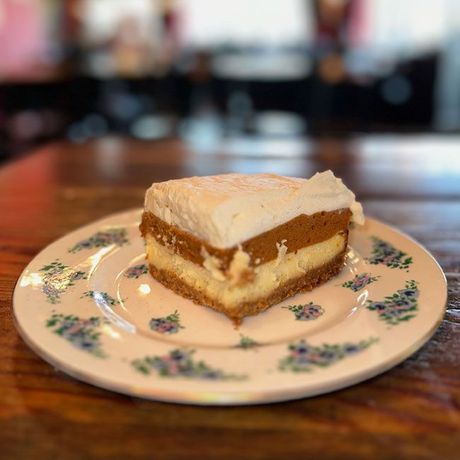 a slice of cheesecake is on a white plate on a wooden table