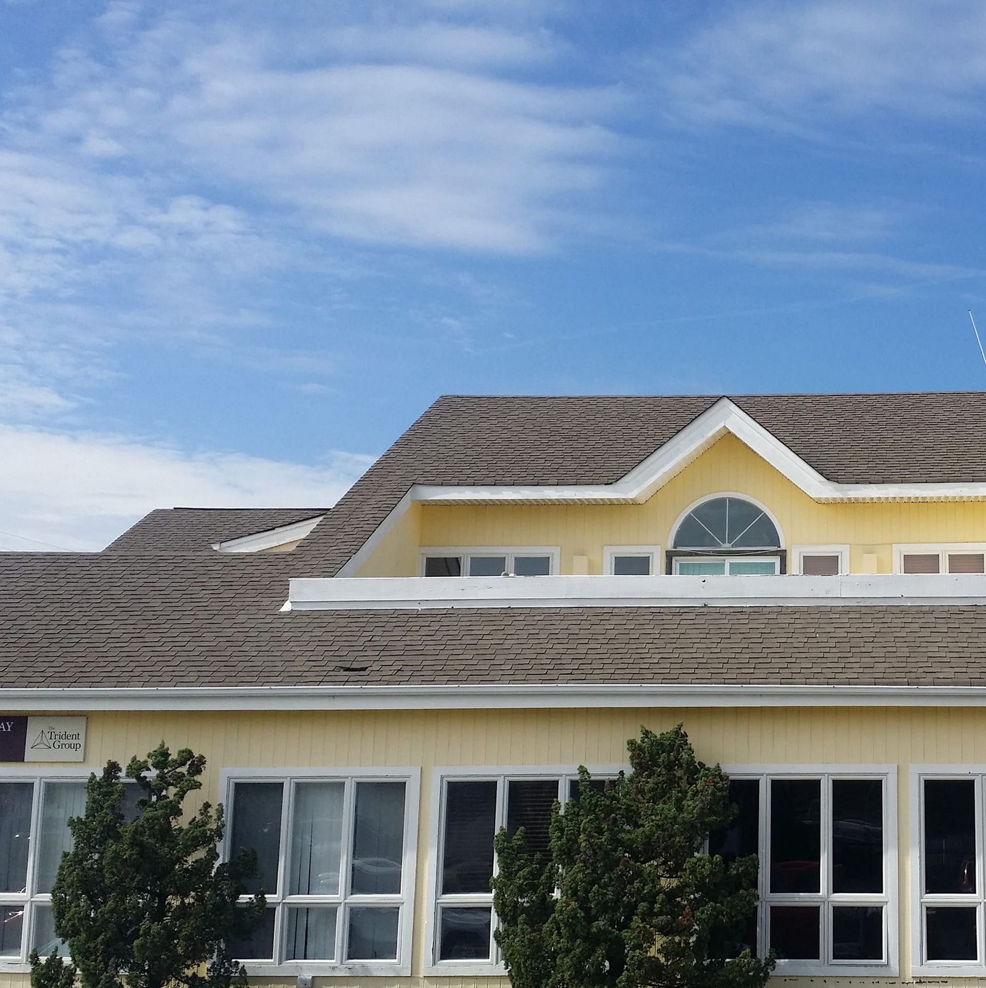 A yellow house with a roof that has shingles on it