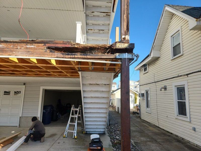 A man is kneeling in front of a garage with a ladder