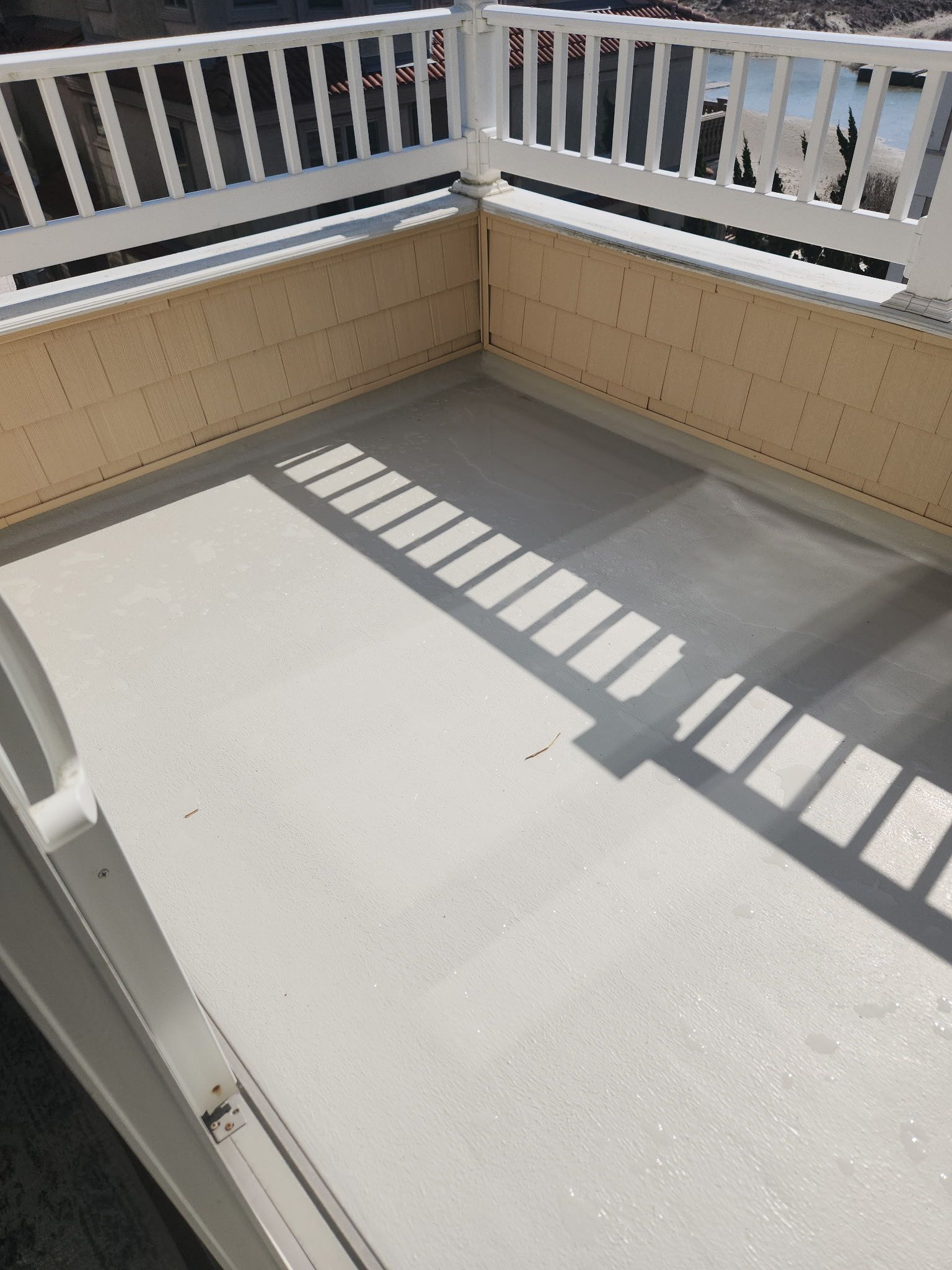 A balcony with a white railing and a shadow on the floor