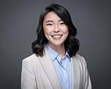 A smiling doctor in a lab coat with a stethoscope around his neck.