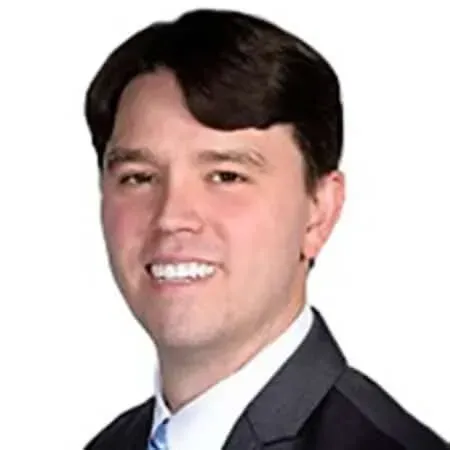 A smiling doctor in a lab coat with a stethoscope around his neck.
