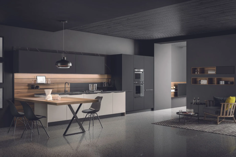 Cucina e zona pranzo moderne a pianta aperta con mobili scuri, isola centrale ed eleganti lampade a sospensione.