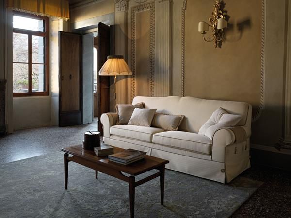 Elegante soggiorno con divano bianco, tavolino da caffè in legno, lampada e ampia finestra.