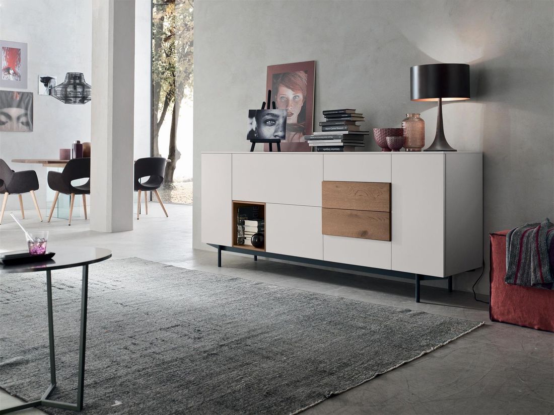 Soggiorno moderno con mobile bianco, dettagli scuri, tappeto e porta aperta che conduce al patio.
