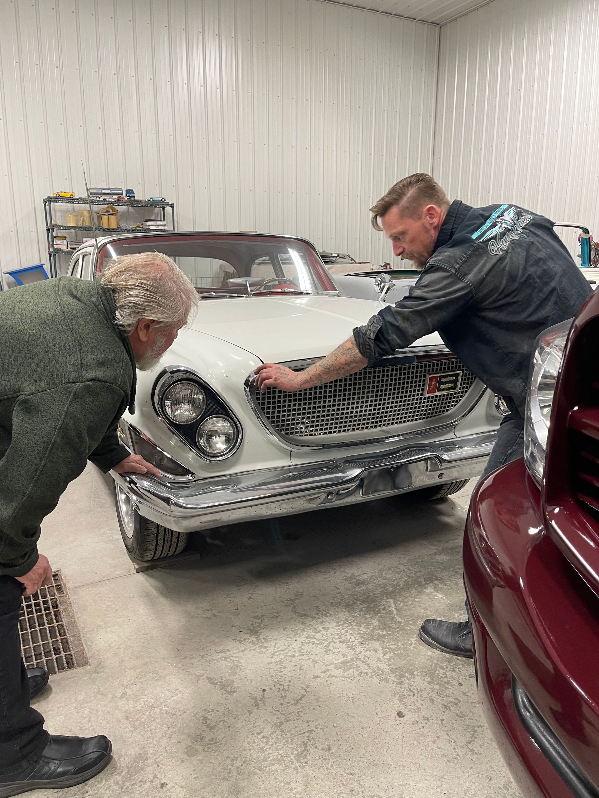 Two men are working on a car in a garage.