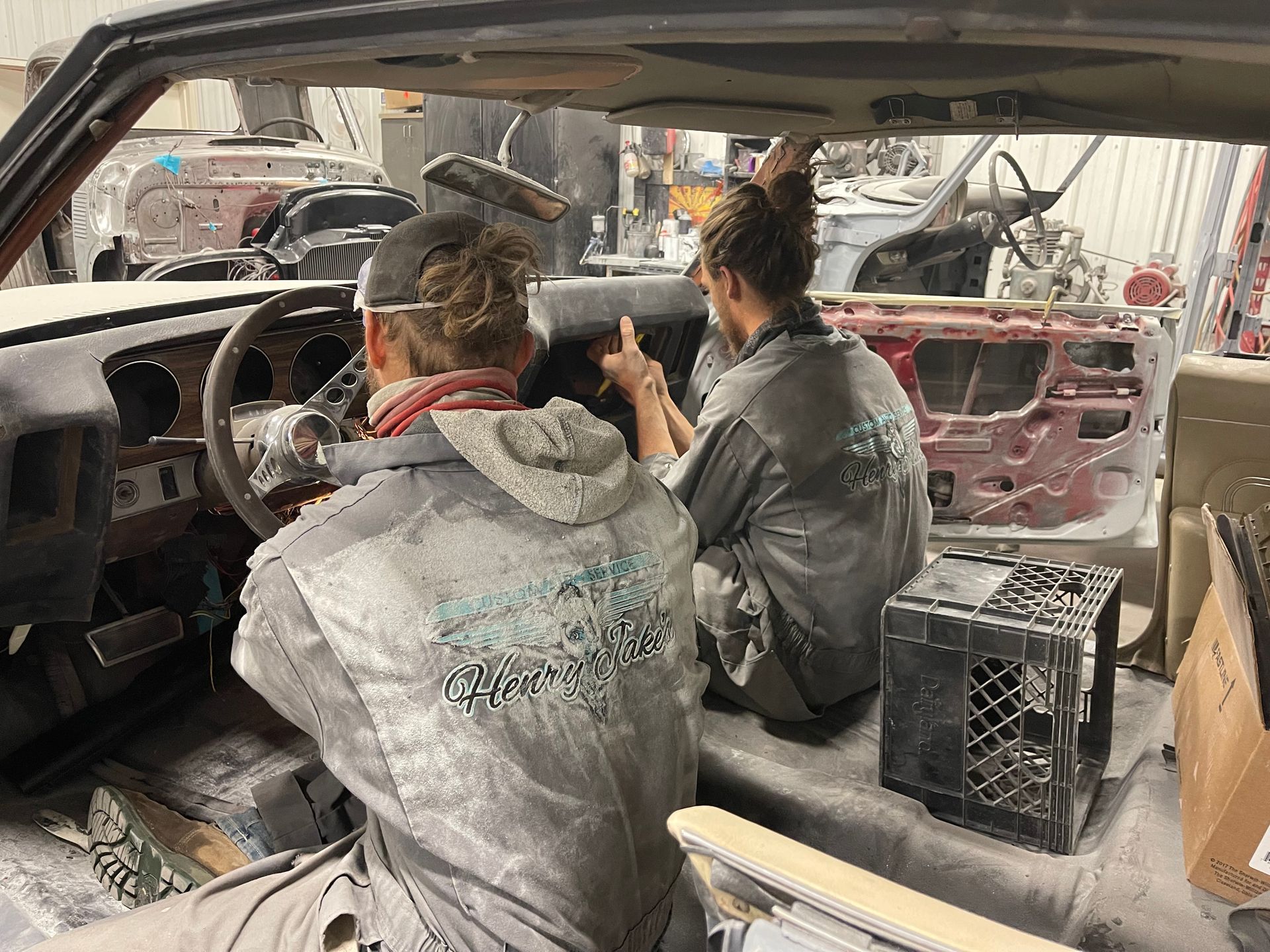 A man and a woman are working on a car in a garage.
