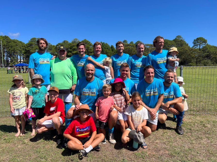 A Group of People Are Posing for A Picture in A Field — Fletcher's Truck and 4WD Repair Centre in Forster, NSW