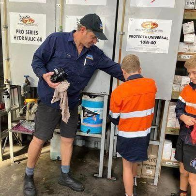 A Man Is Standing Next to Two Children in A Garage — Fletcher's Truck and 4WD Repair Centre in Forster, NSW