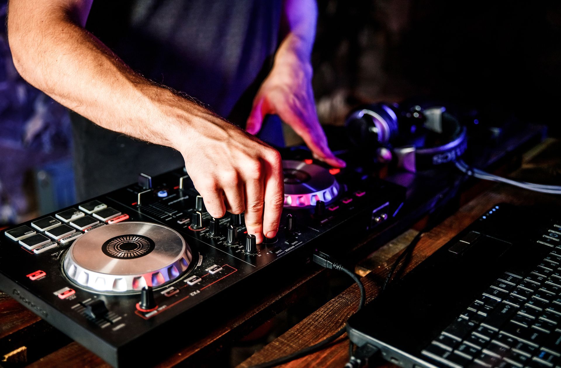 DJ plays live set and mixing music on turntable console at stage in the night club