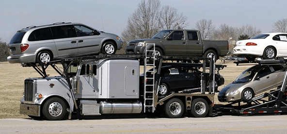 Car hauler truck transporting multiple vehicles on a highway.