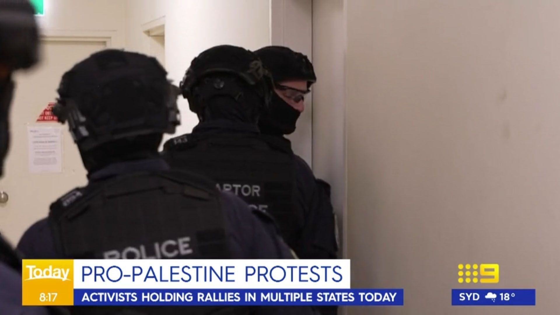 Police officers in black tactical gear entering a building during pro-Palestine protests.