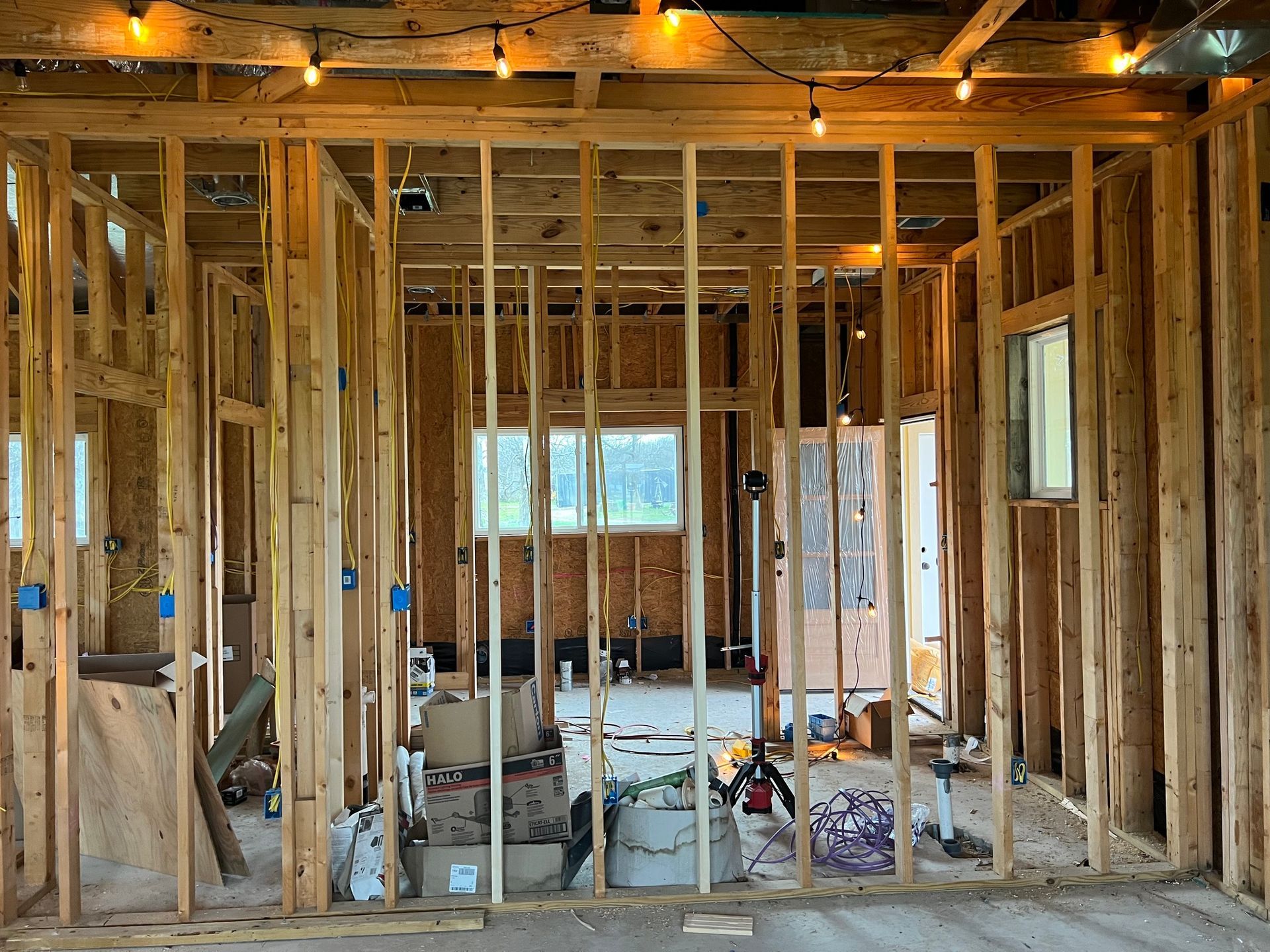 Hands using pliers to cut wire in an open electrical panel with blue and yellow wires and circuit breakers.