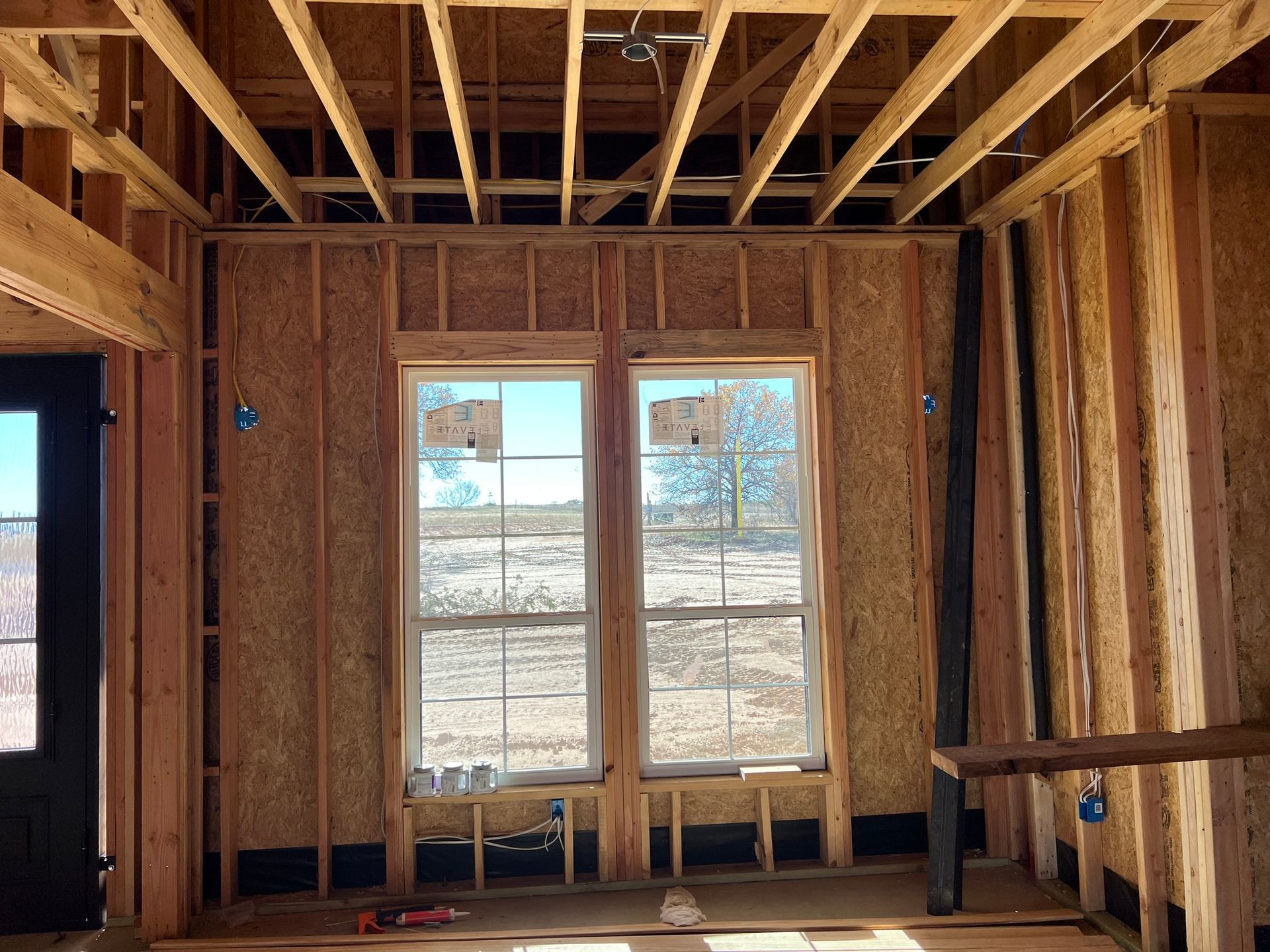 Person working on electrical wiring inside an open gray metal box on a wall, with wires of various colors.