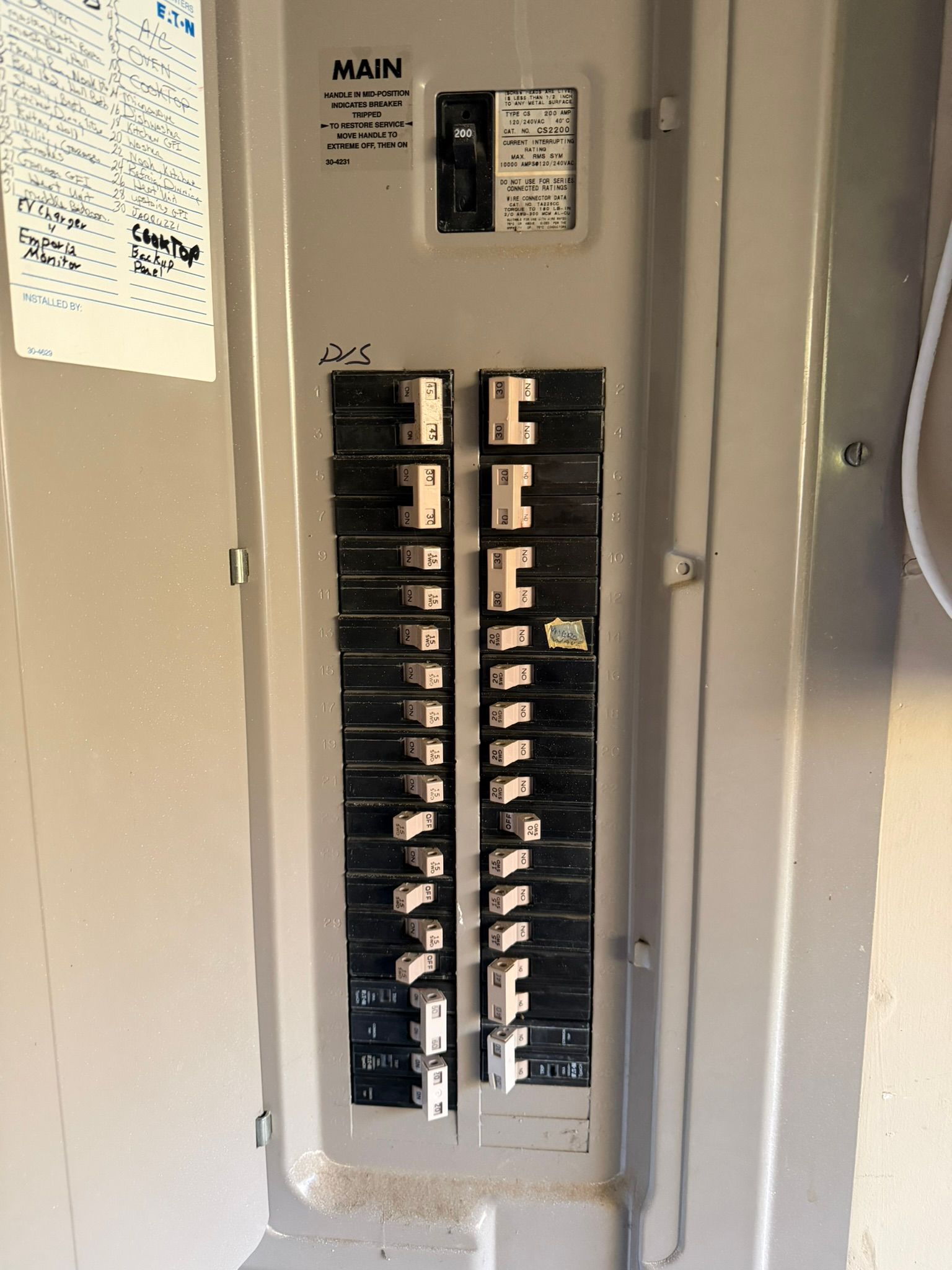 Electrical control panel with wires, breakers, and switches. Inside a gray metal box, open.