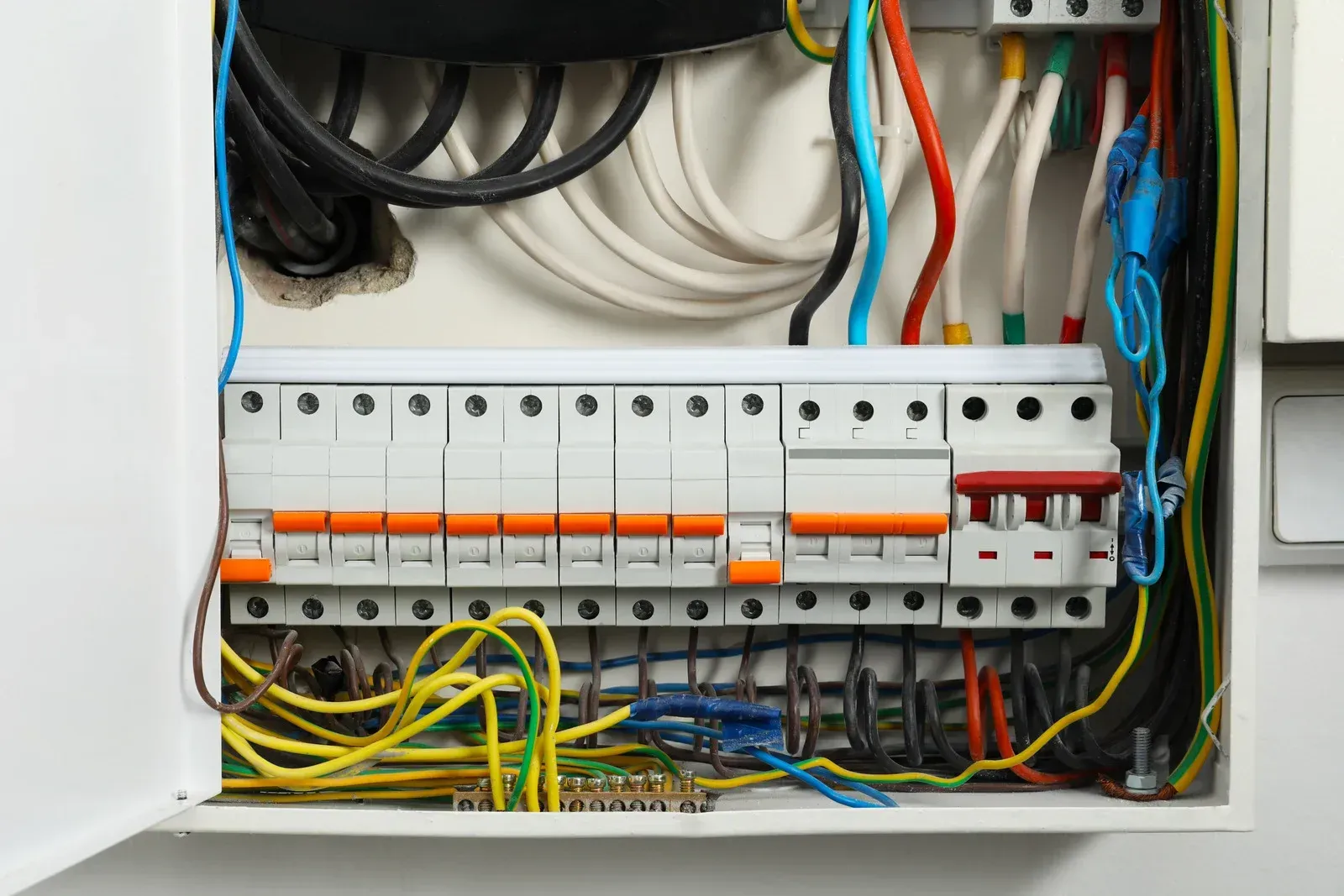 Open electrical panel with various colored wires and circuit breakers.