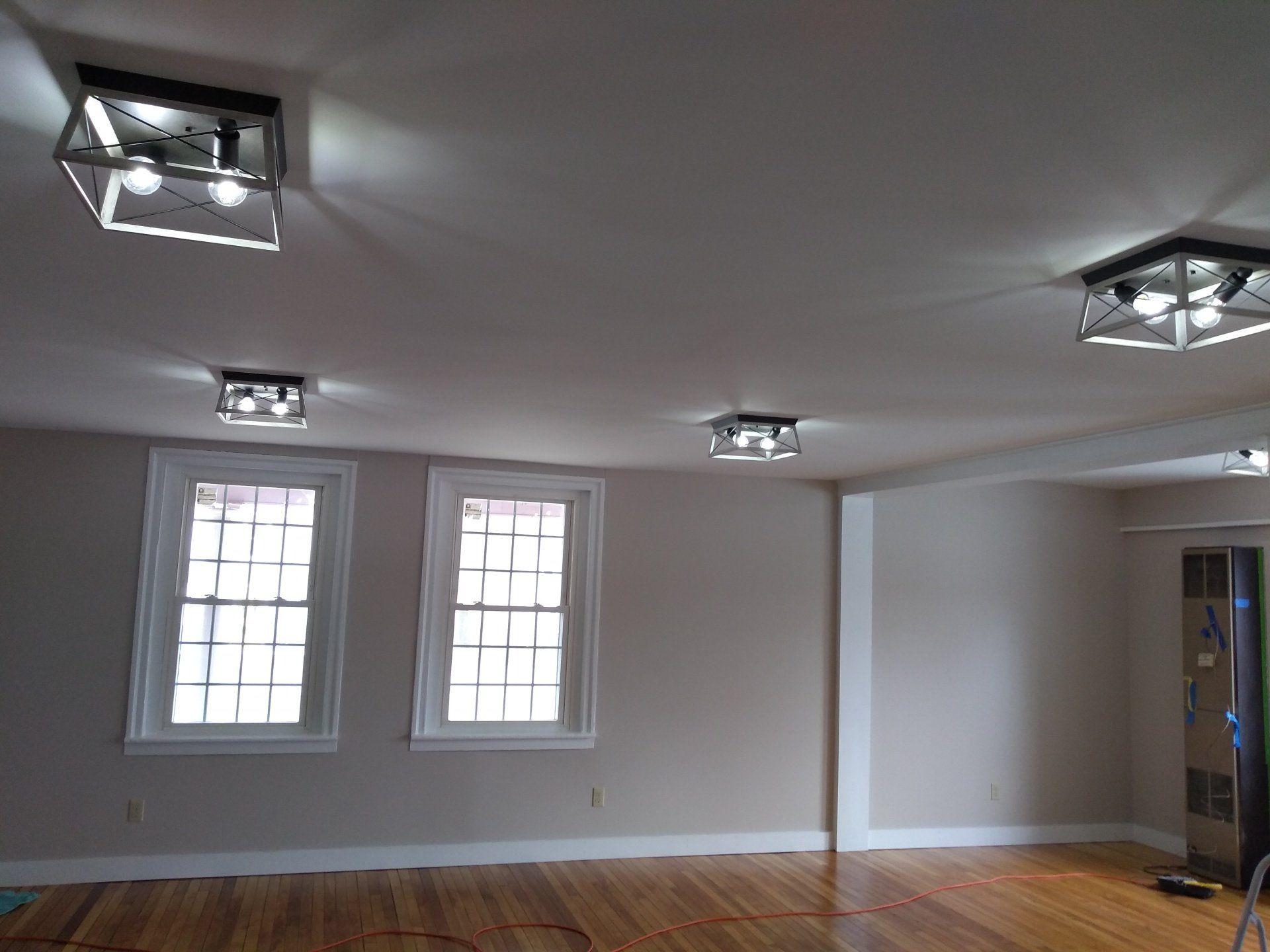 a white room with hardwood floors and ceiling lights .