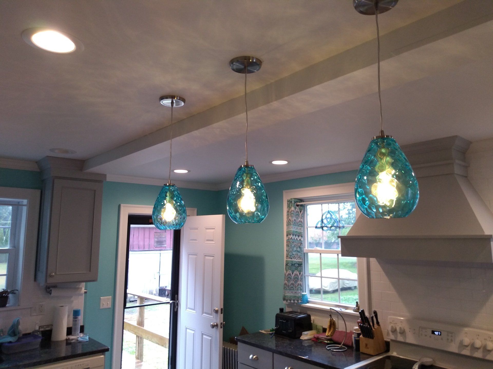 a kitchen with blue pendant lights hanging from the ceiling